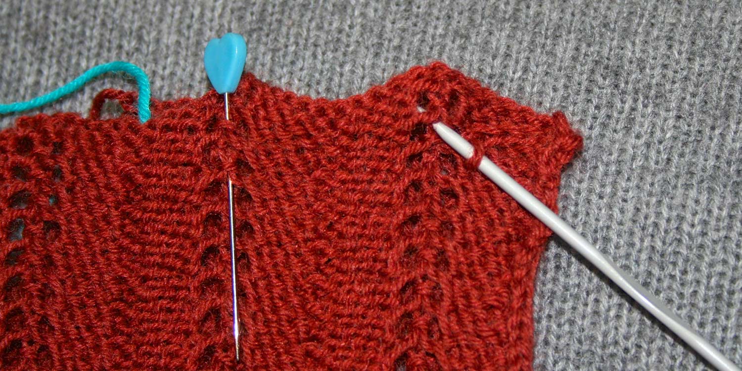 Crochet hook is inserted in knitting several rows below the bind-off edge, but in line with the straight line of seam stitches.