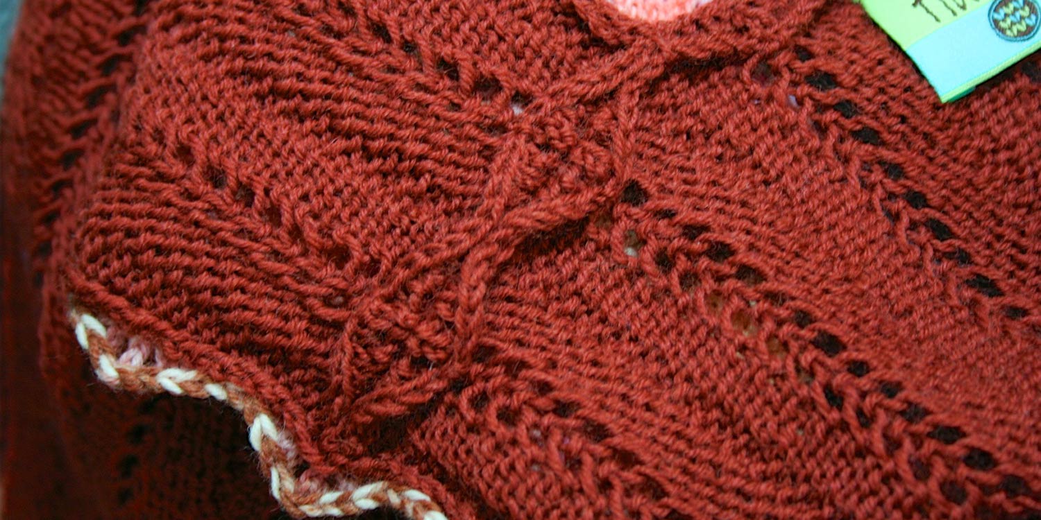 Wrong side of garment with scalloped seam allowance on shoulder seam spread open.