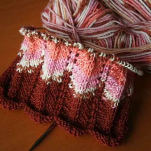 Small sleeve on the needles in a lacy, scalloped stitch pattern.