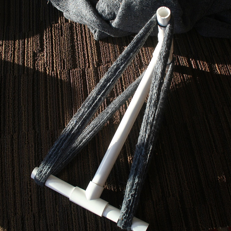 Grey yarn wound around a white niddy noddy.