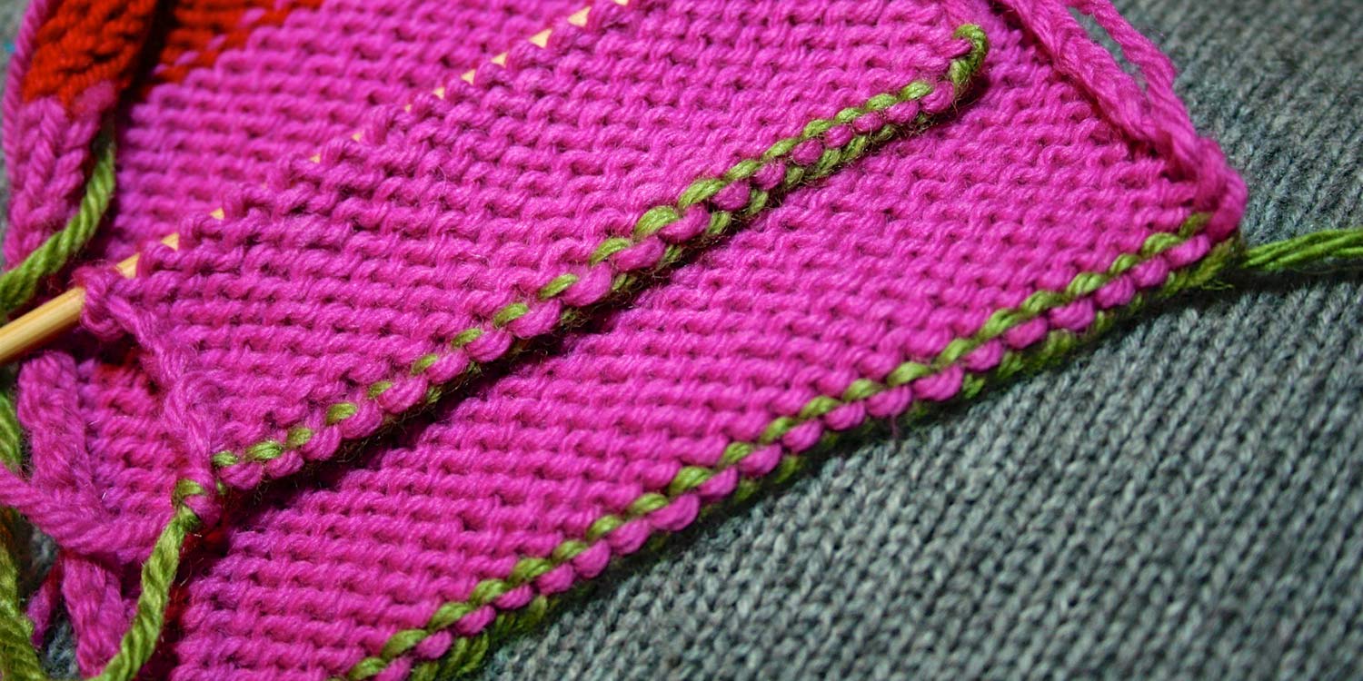 Wrong side of two swatches lying on top of one another showing the same edging; the top one worked as a cast on and the other a bind off.