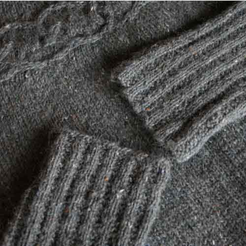 Cuffs of two sleeves laying on top of sweater so both edges can be compared; they both look the same.