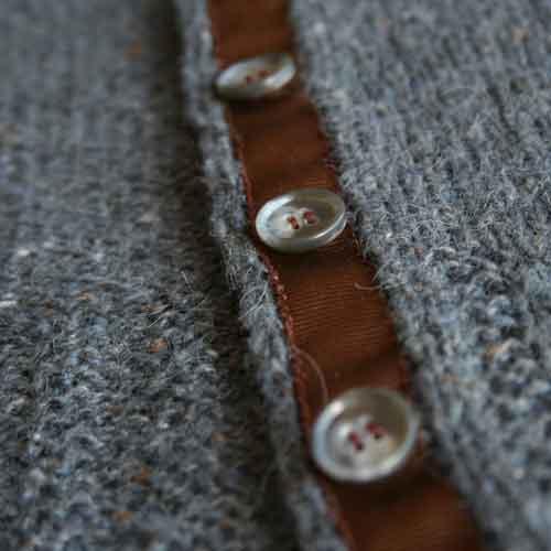 Close up shot of three buttons sewn to buttons band lined with gros grain ribbon.