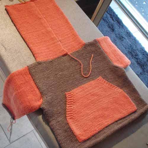 Partially completed baby hoodie with the hood section blocking on an ironing board.