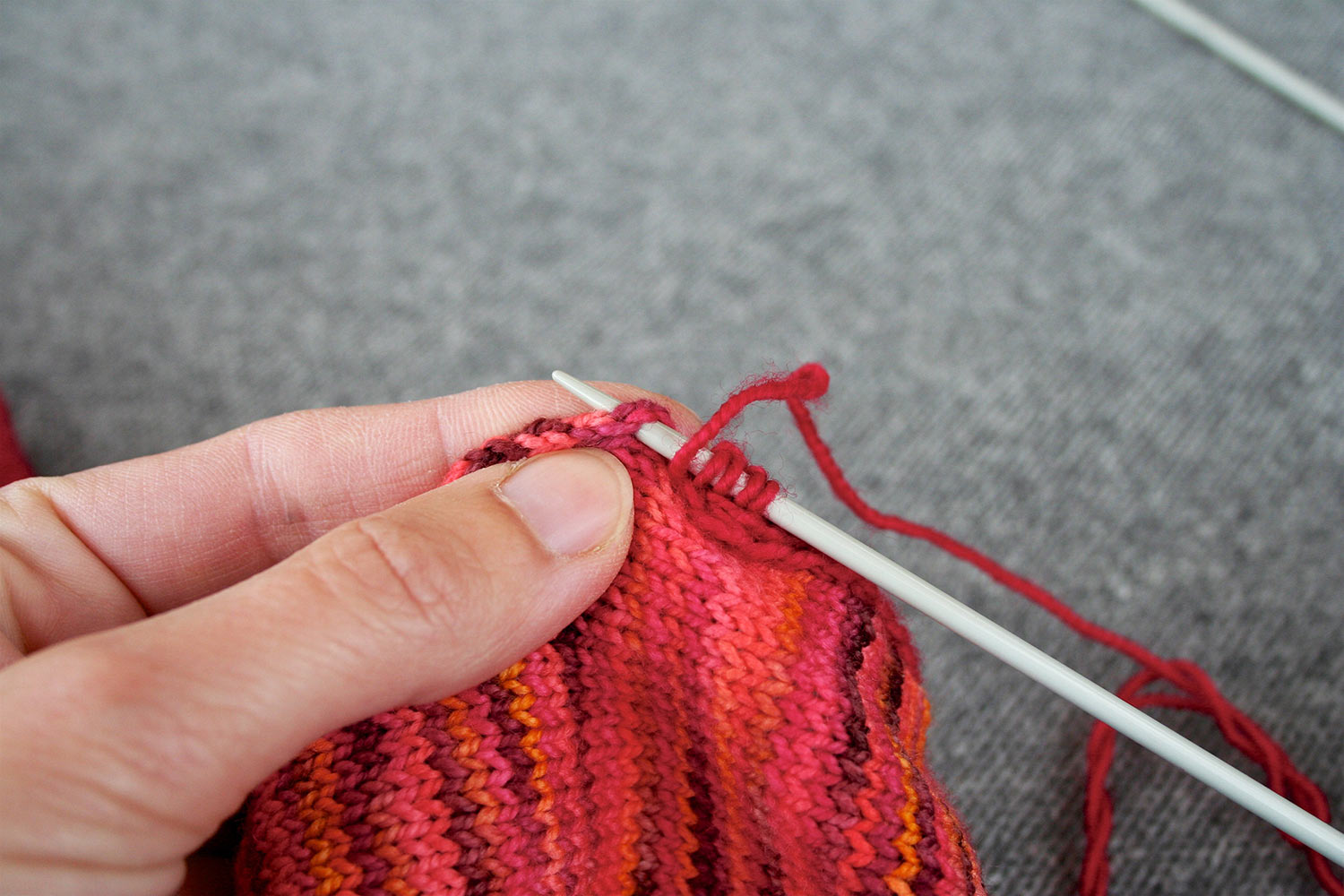 Right needle with four stitches is inserted into the selvedge edge near where i-cord is attached; yarn is at the front after last stitch worked.