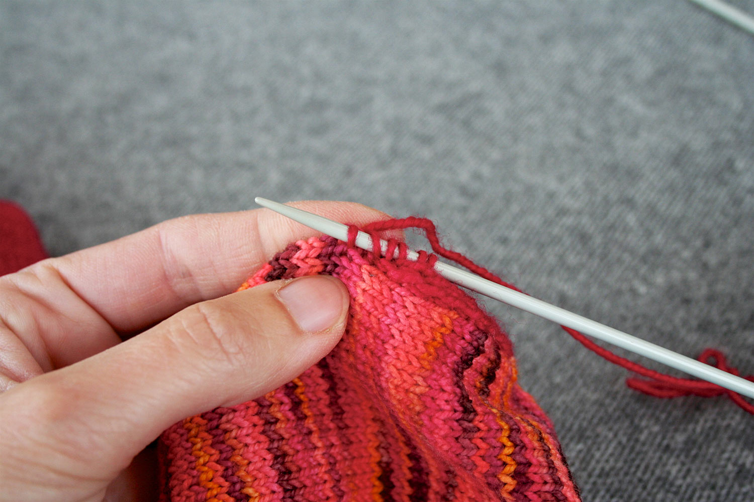 Six stitches on right needle and left hand holding up knitting.