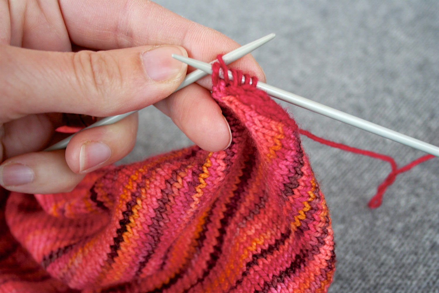 Left needle inserted into second stitch from end on right needle, preparing to pass it over last stitch on right needle.