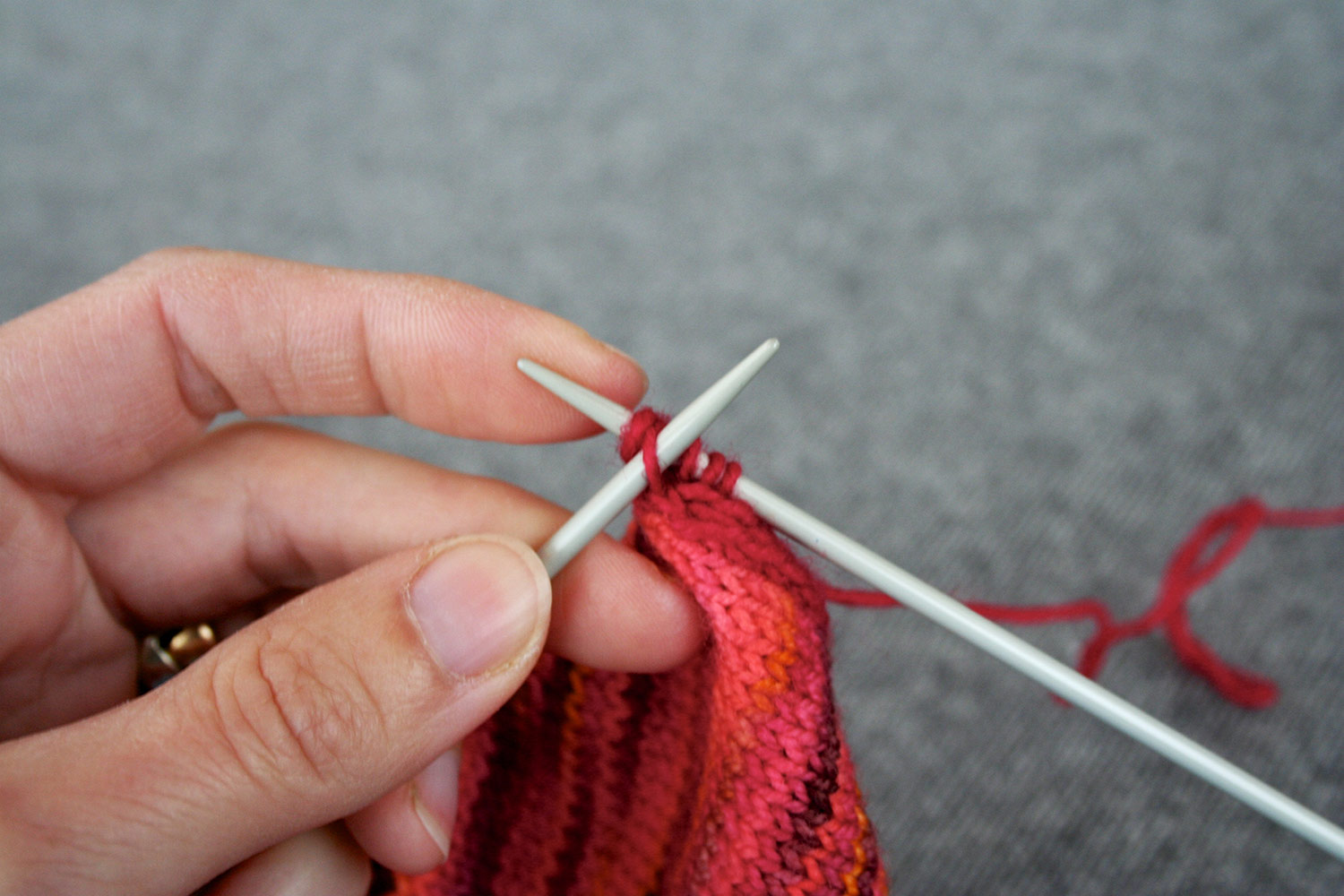 Left needle inserted in second stitch on right needle (this was the slip stitch), preparing to pass it over last stitch.