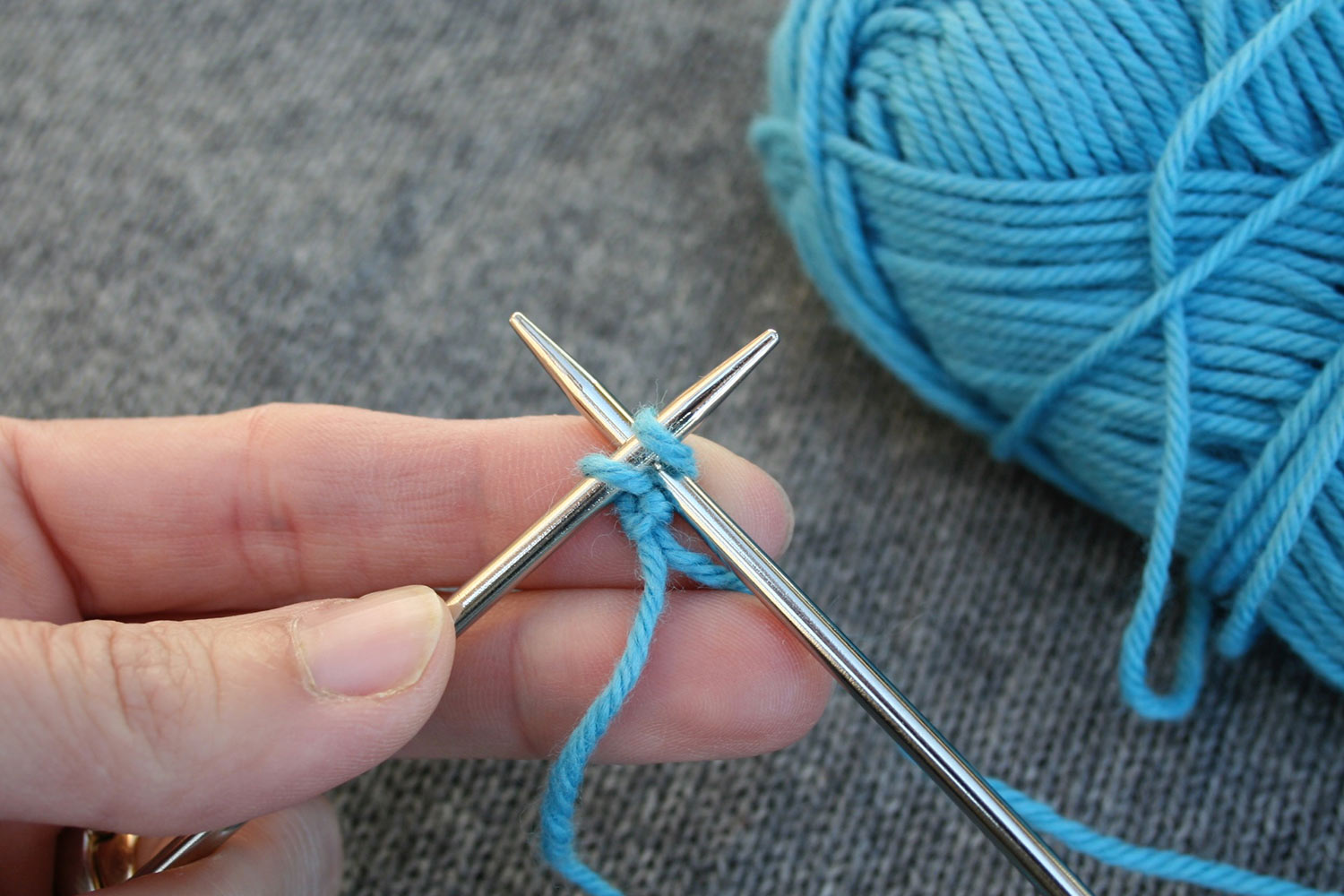 Right needle inserted between two stitches on left needle.