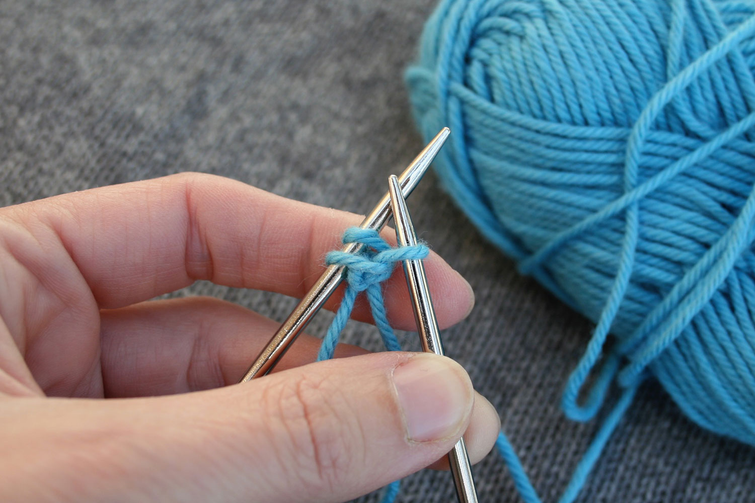 Right needle with stitch on it that was created from between two stitches on left needle.
