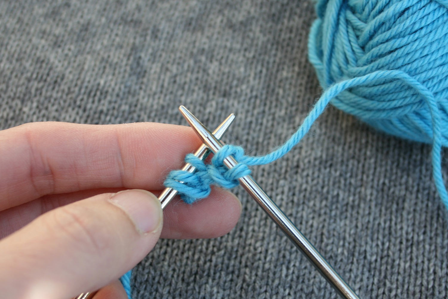 Right needle with two knit stitches and left needle with three stitches.