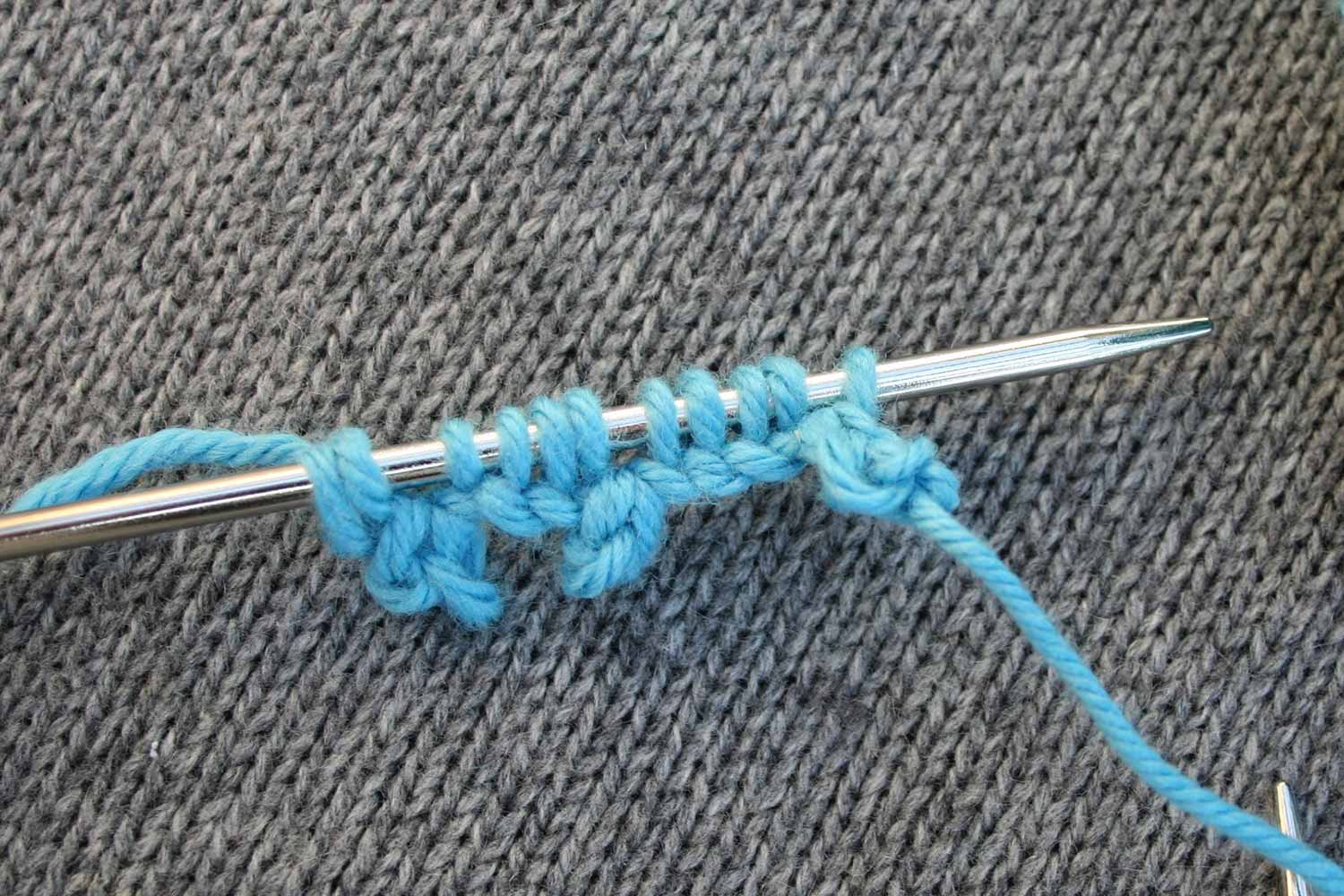 Eleven stitches cast onto a needle with three picot bumps; there are little spaces in the cast on where each picot bump is created.
