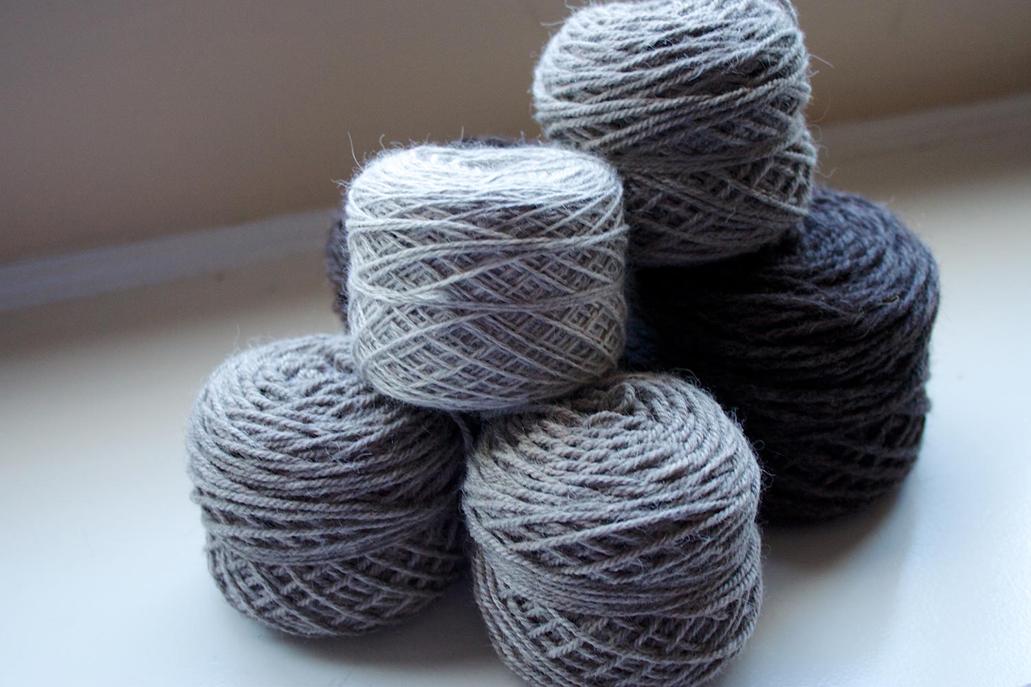 Pile of yarn cakes in light medium and dark natural alpaca colours.
