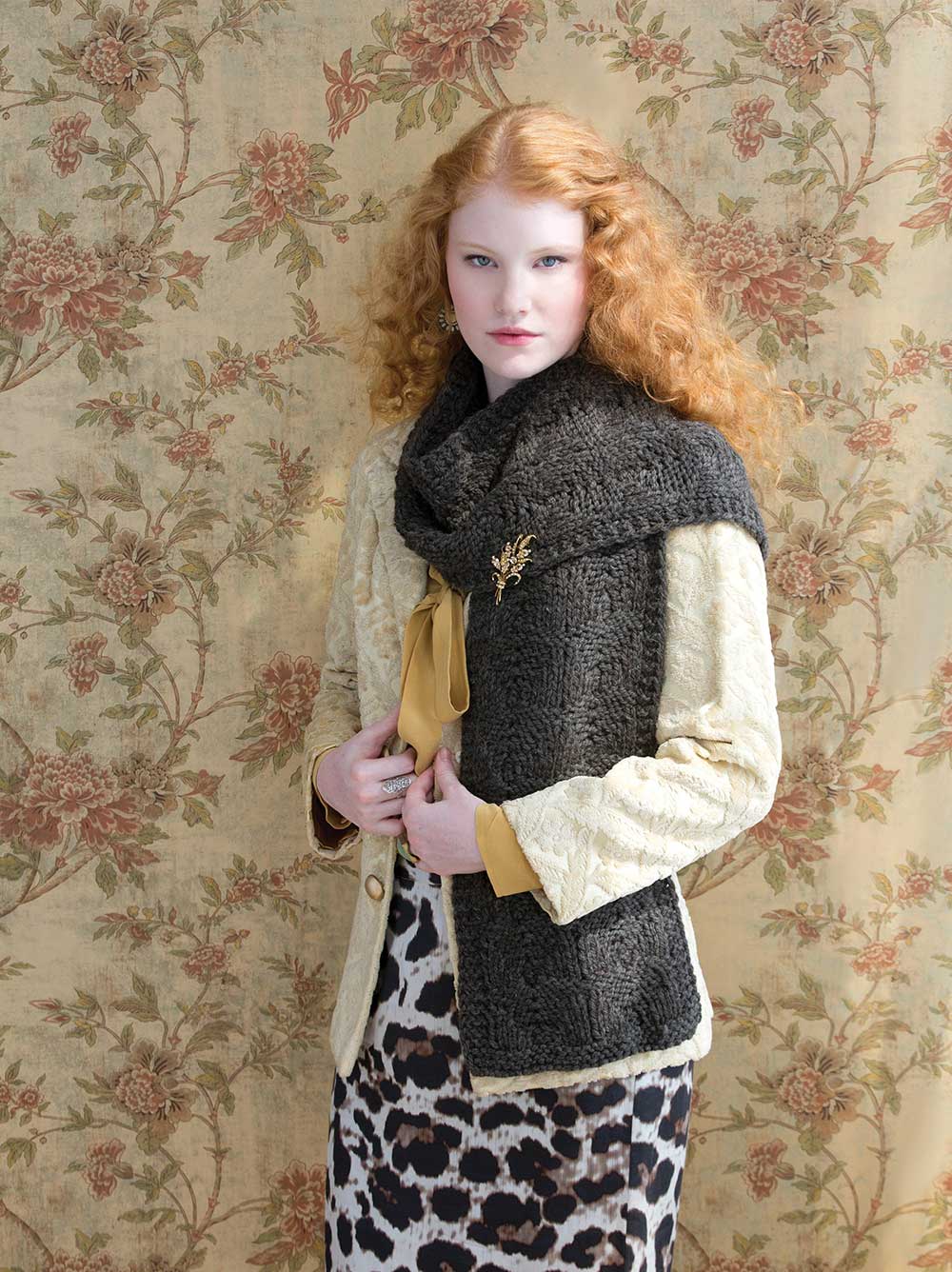 Red-haired woman wearing a chunky dark brown scarf flung over her shoulder.