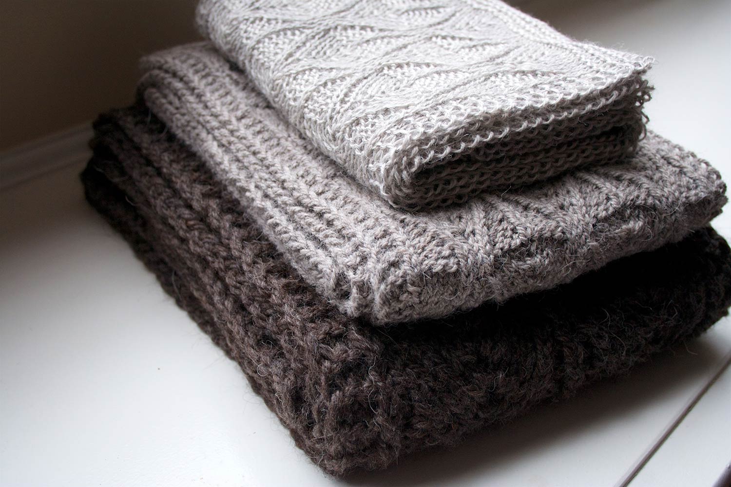 Pile of folded up scarves in neutral colours.