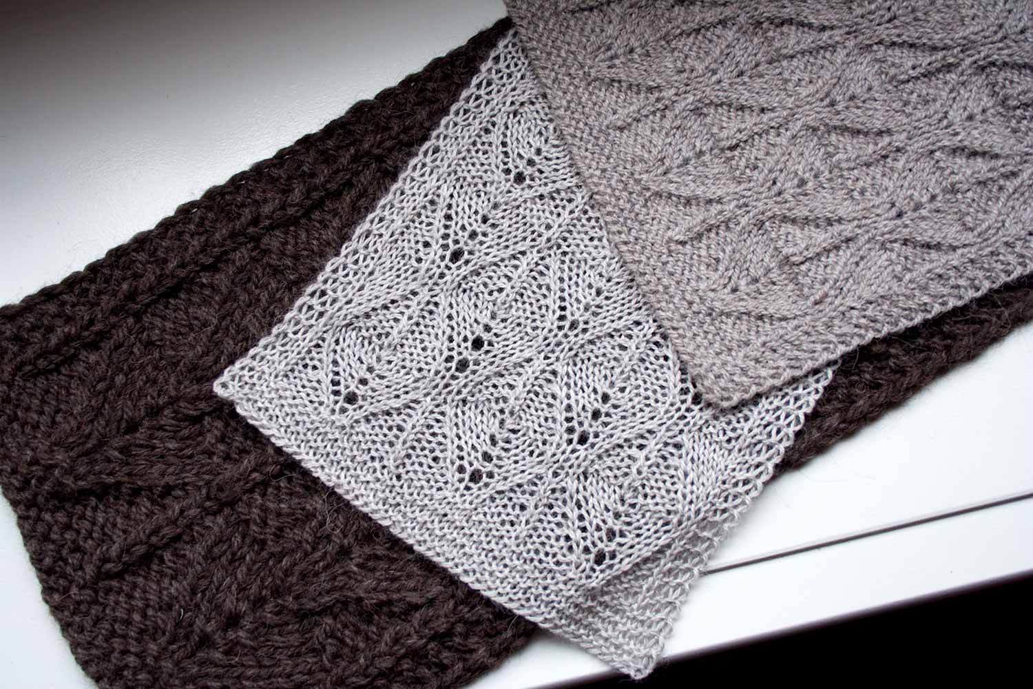 Three scarves of different weights laid one over the other, each with similar stitch patterns.