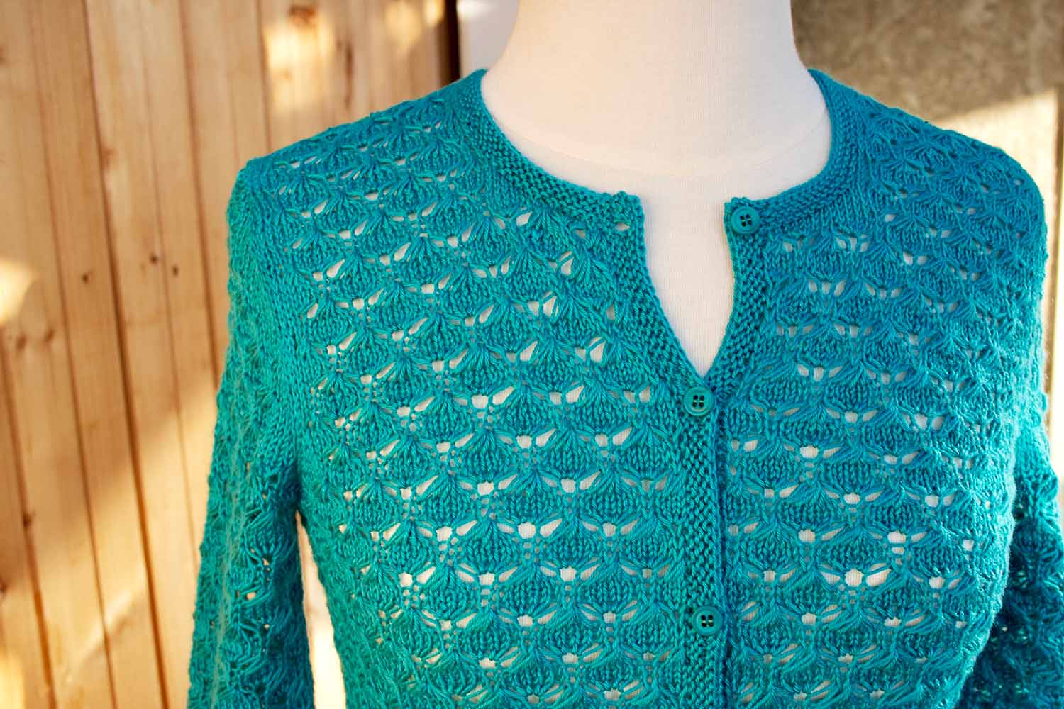 Upper torso front view of Classic Lace Cardigan on dress form with top button unbuttoned.