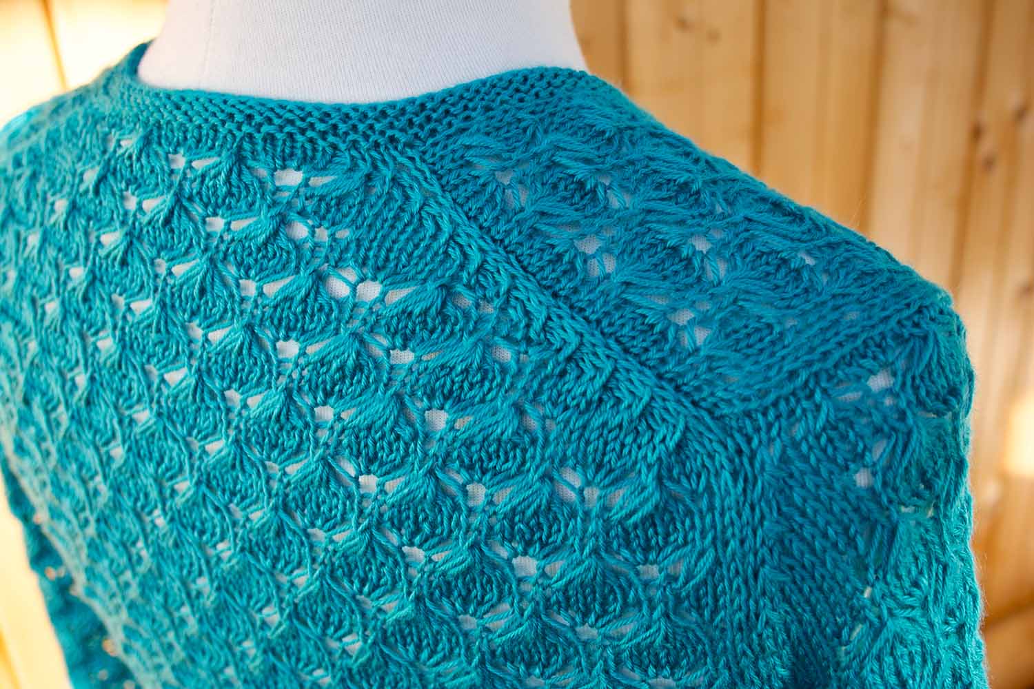 Detail shot of English tailored shoulder seam on all-over lace cardigan on dress form.