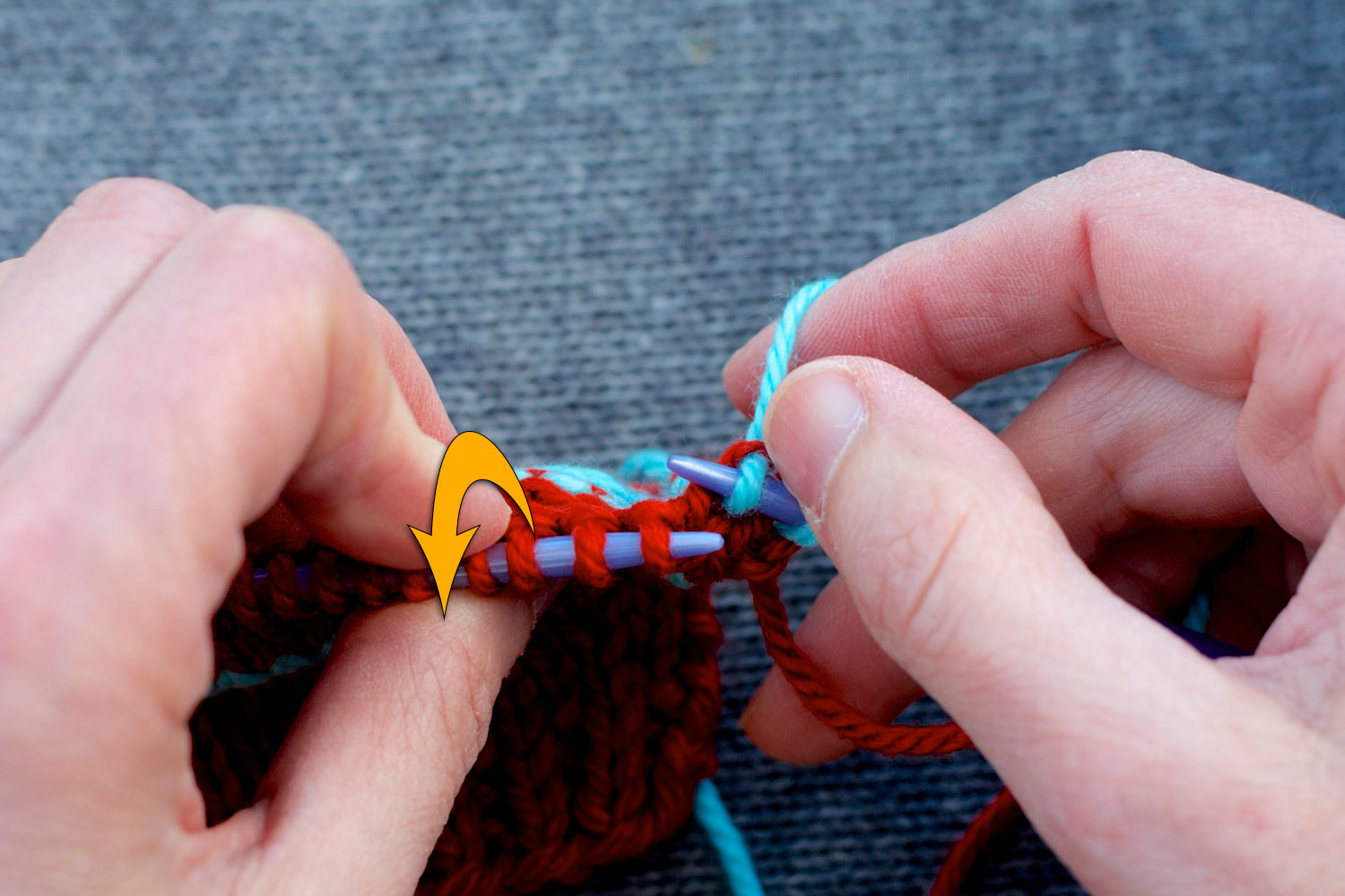Stitches on the knitting needles with left needle tilted forwards (as indicated by large yellow arrow) to show purls bumps on wrong side.