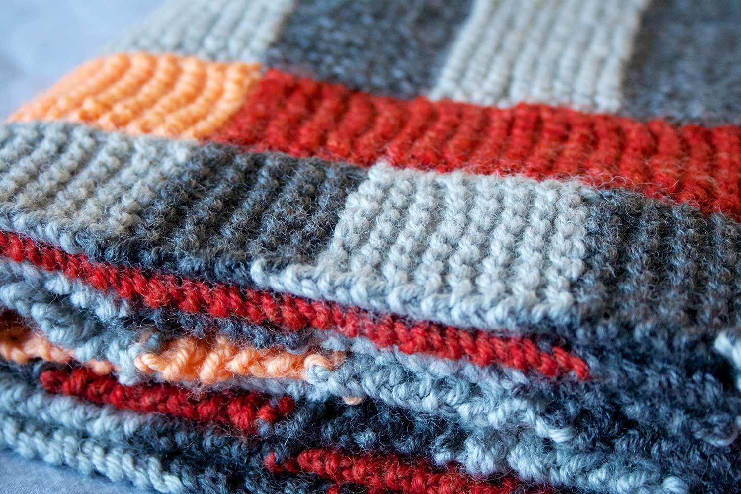 View of the edges of a folded up garter stitch blanket with stripes.