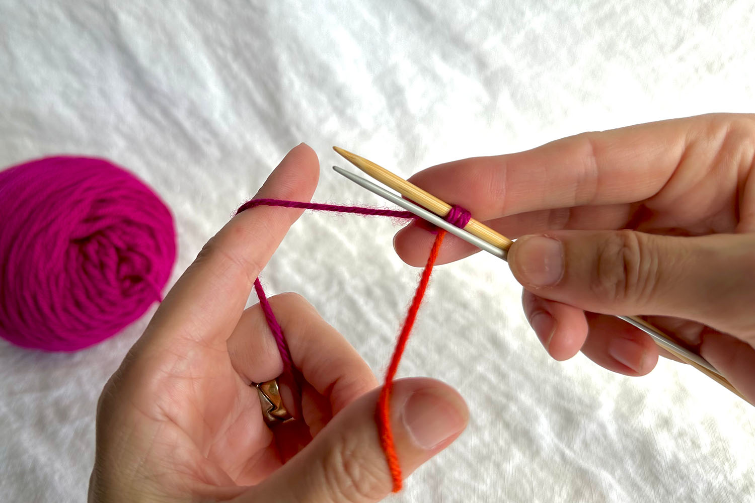 Setup for Double Needle Cast On; two stitches on gauge needle and a smaller needle held underneath gauge needle and in front of yarn.
