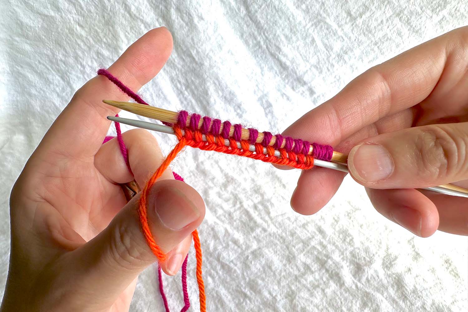 Several stitches cast onto larger (gauge) needle and bottom edge of cast on around smaller needle.