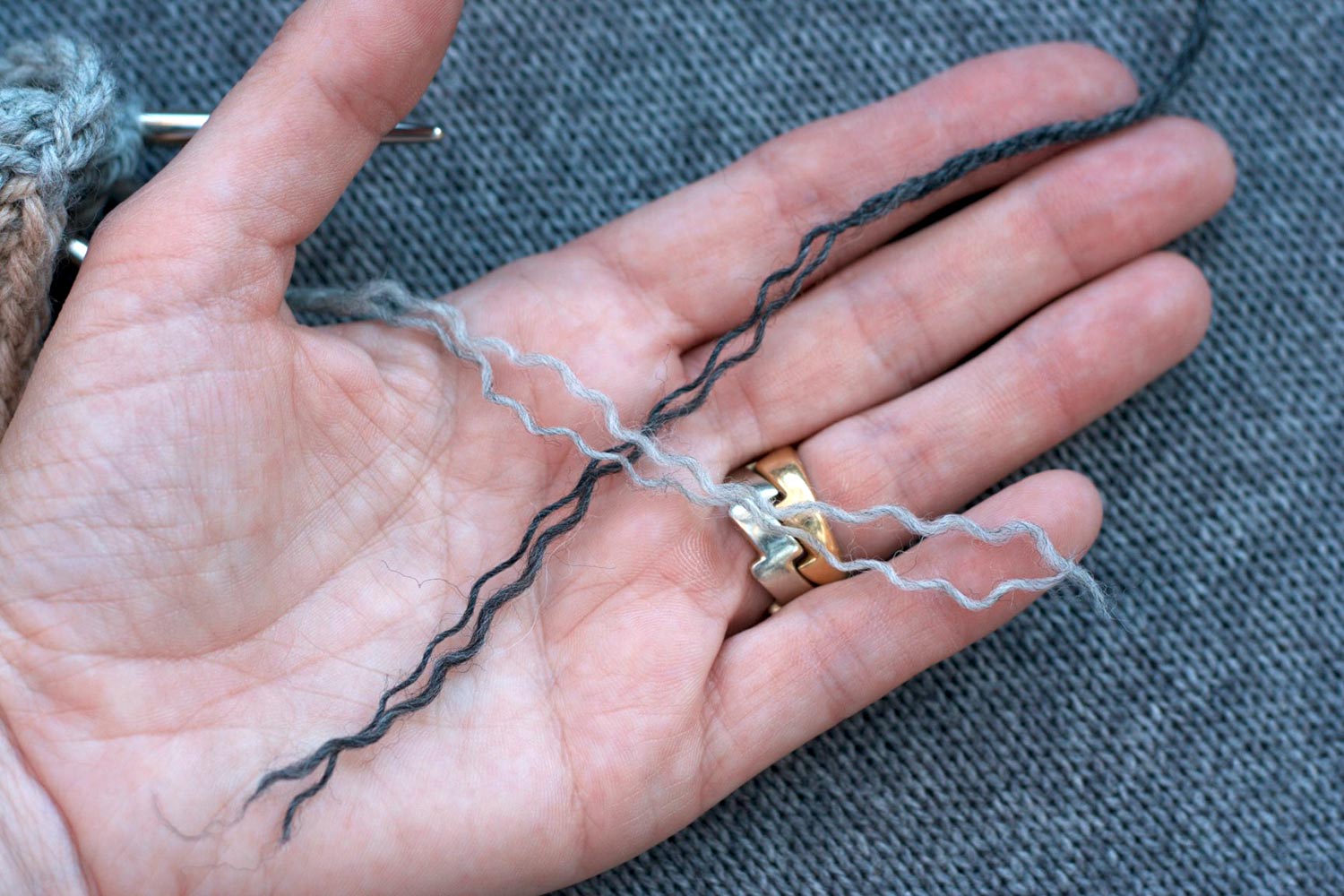 Hand open with palm up and unplied yarn from ends of two different colours of yarn crossed on palm.
