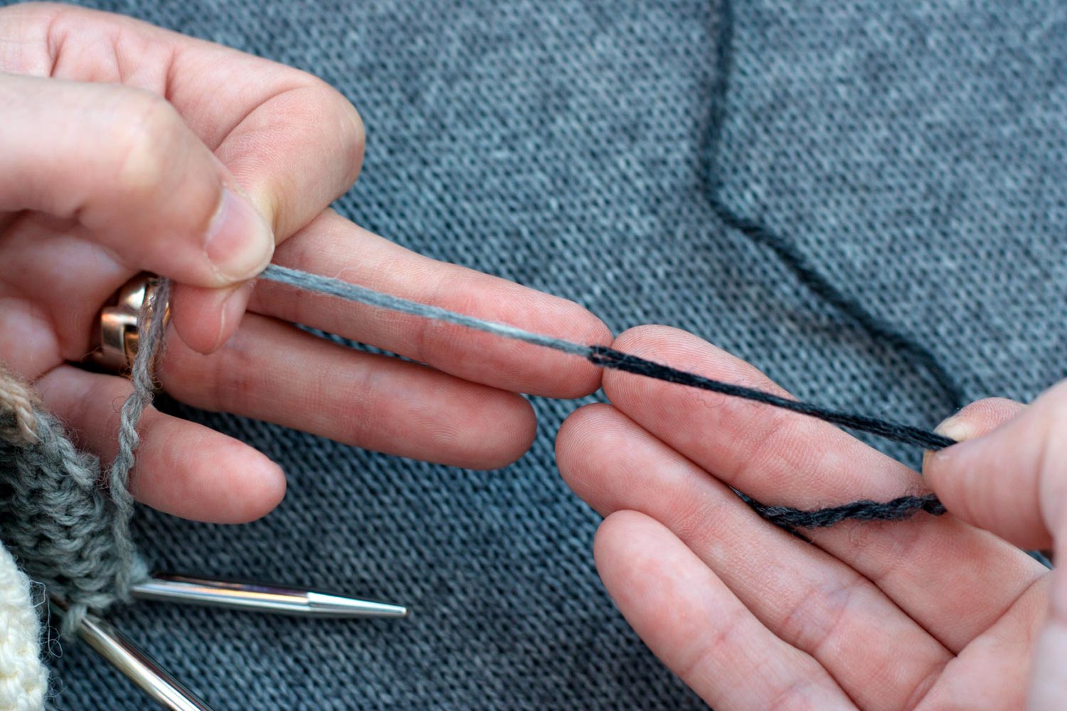 Two loops of yarn in different colours, held taught between two hands and wet.