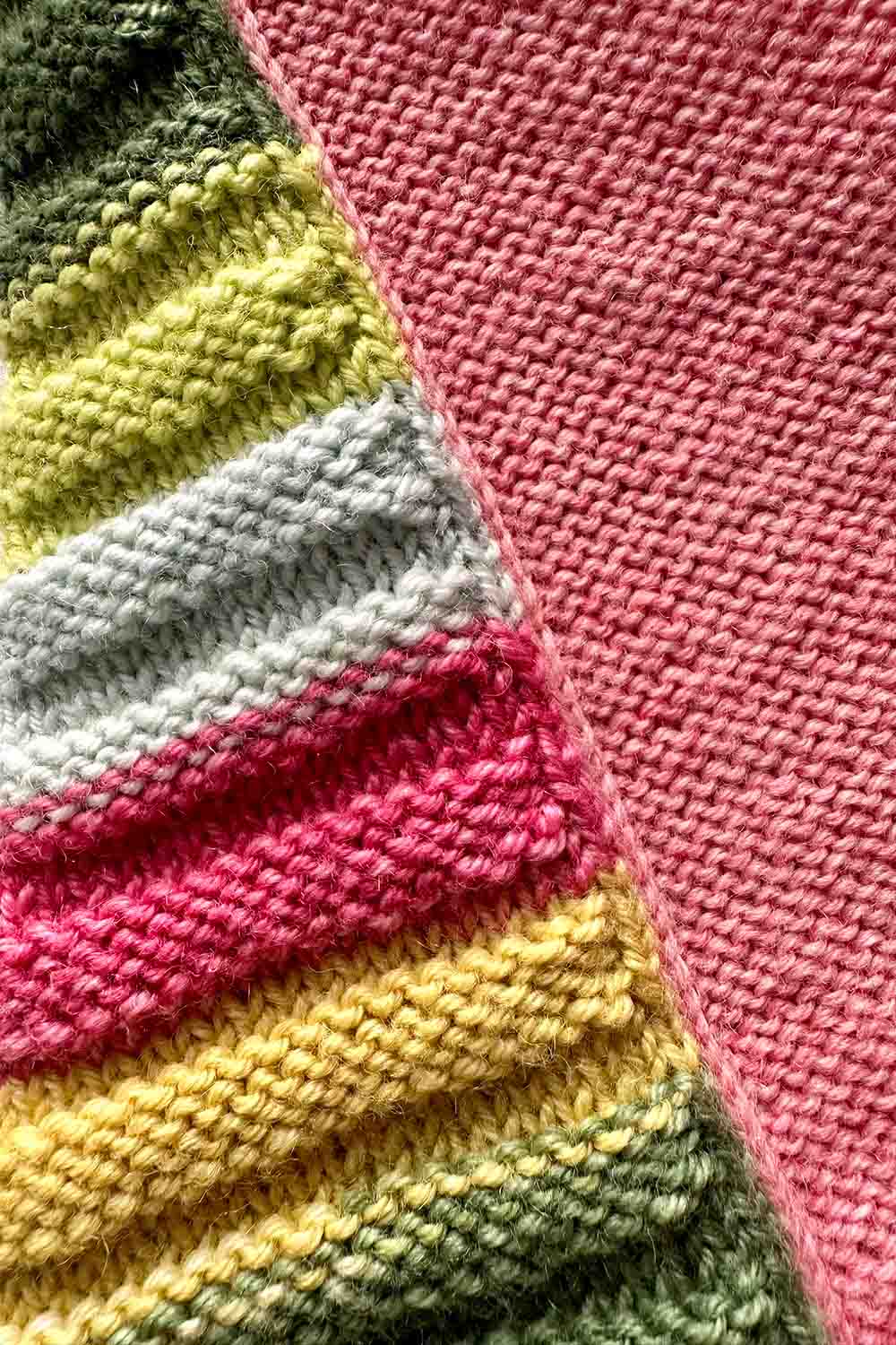 Detail shot of side seam showing ridged textured front and Reverse Stocking Stitch back each framed by a column of knit stitches at the seam.