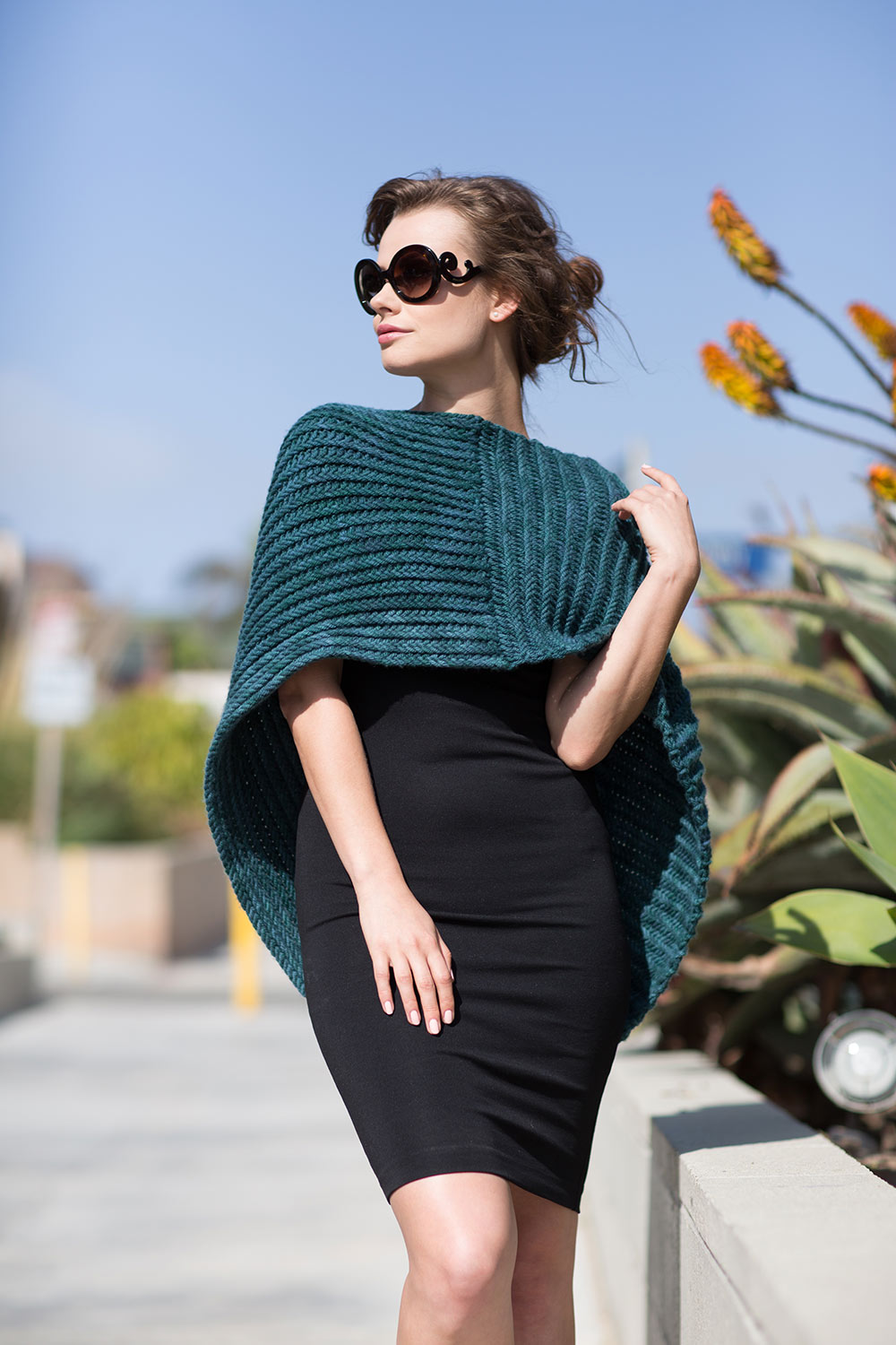 Large cowl draped over front and shoulders and hanging in the back, worn like a cape/poncho. Textured ridges run horizontally on one half and vertically on the other half.