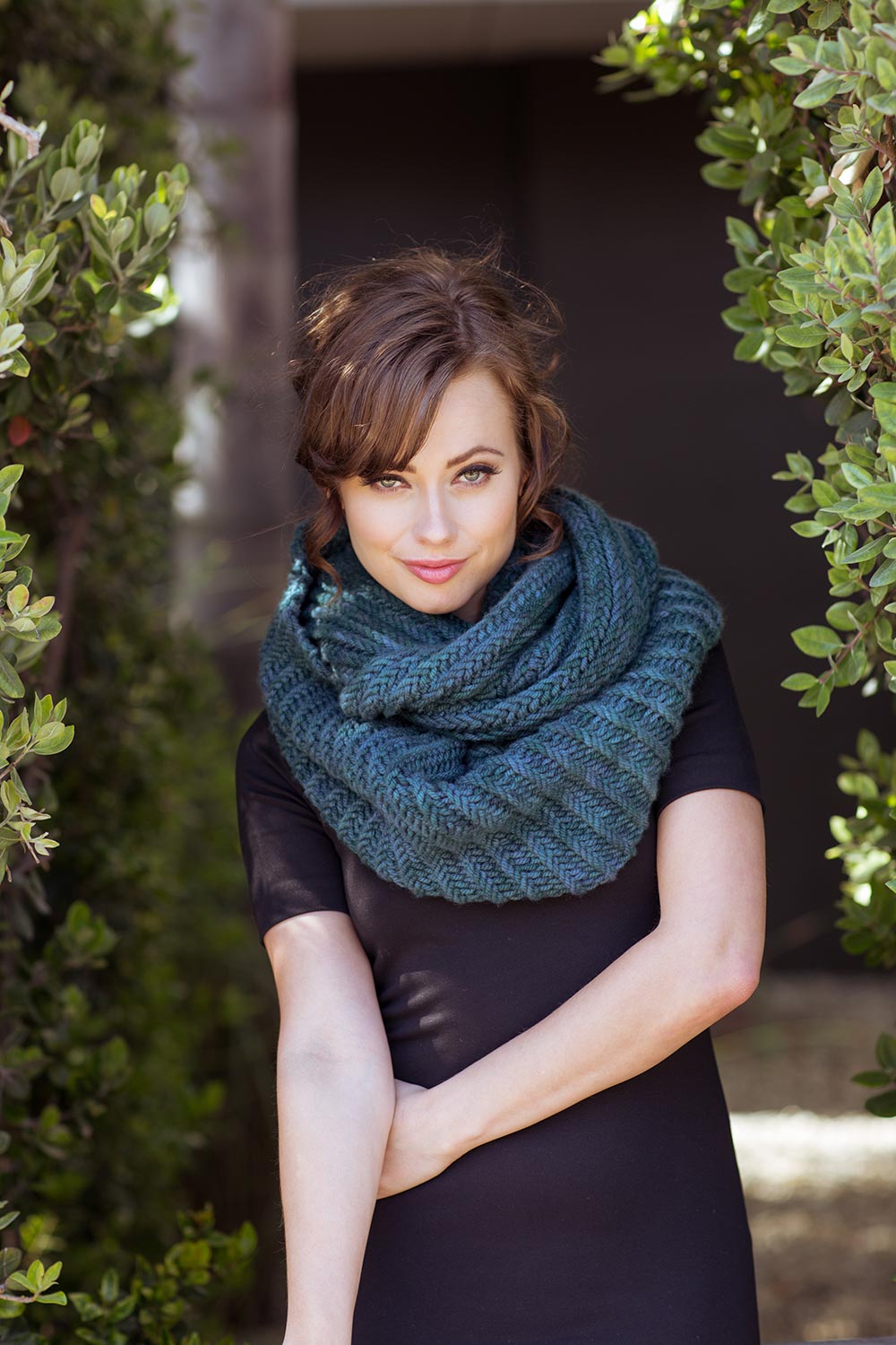 Huge bulky cowl is wrapped twice around the neck covering both the neck and shoulders.