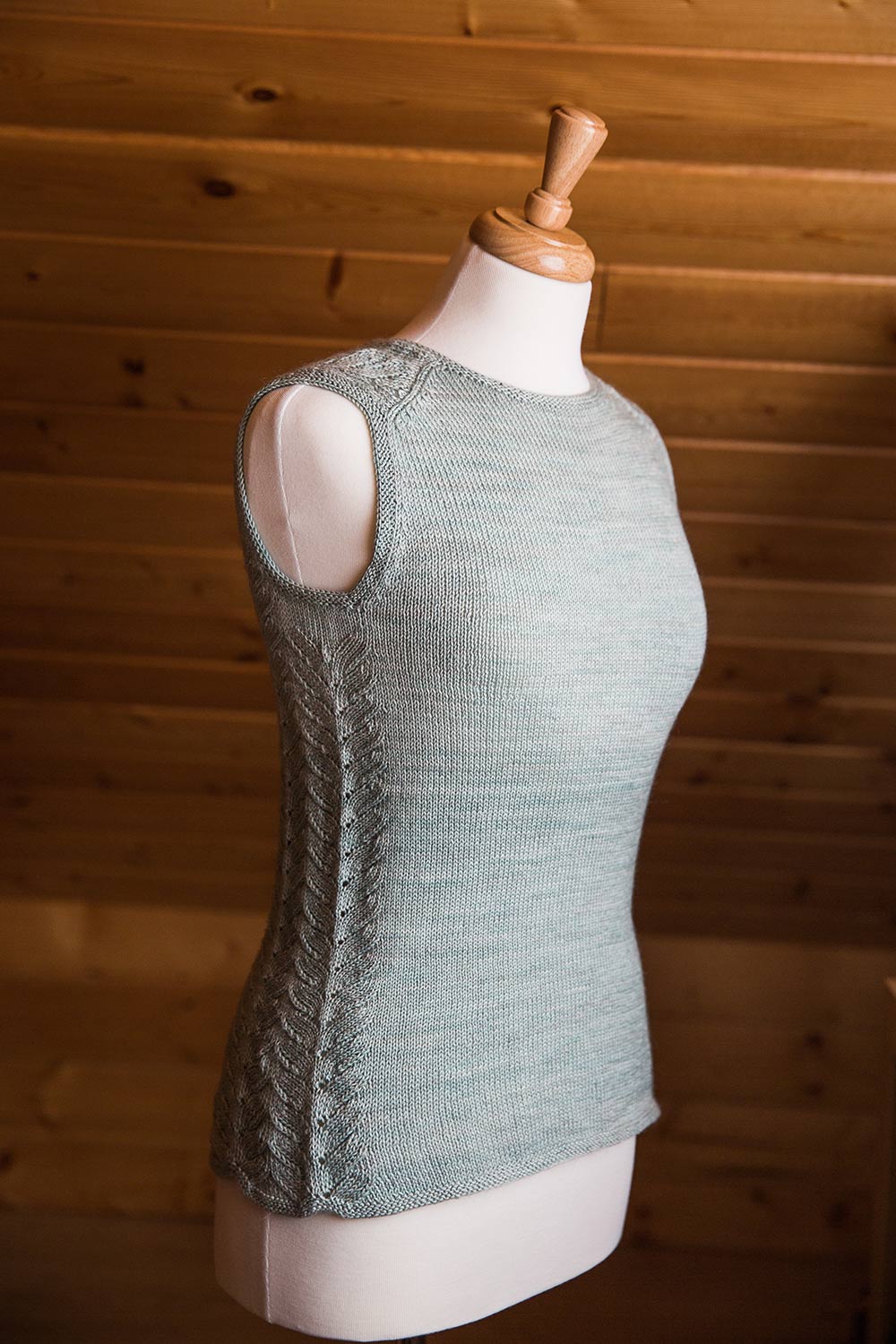 Front and side view of sleeveless shell on dress form. Front is plain stocking stitch while lace wraps around the sides and over the shoulder ending with an English tailored shoulder seam.