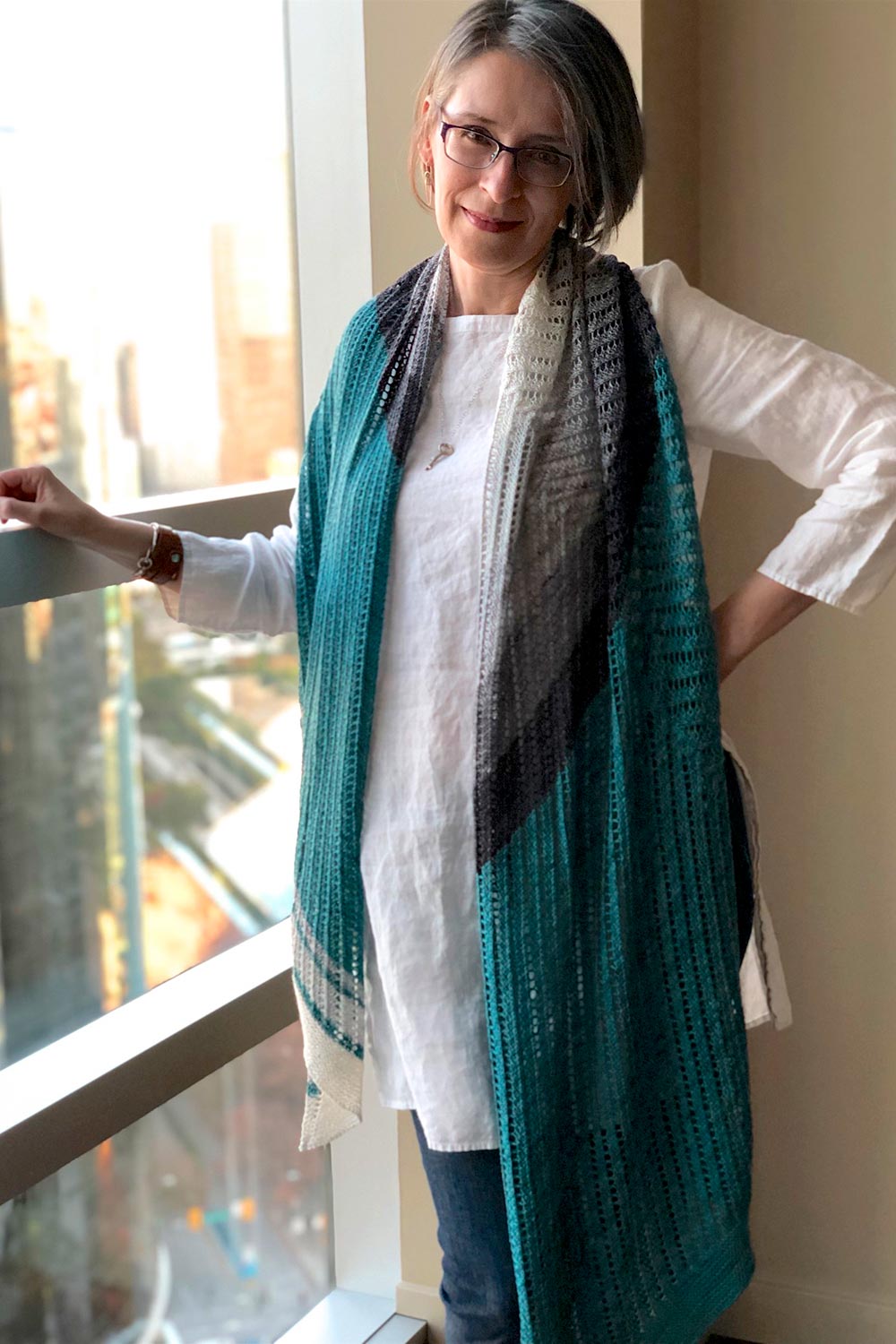 Long shawl drapes around back neck and hanging to hip on one side and knees on the other side.