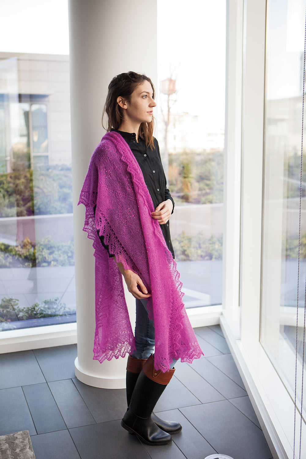 Long rectangular shawl with lace edging is draped over one shoulder and hangs to knee length.