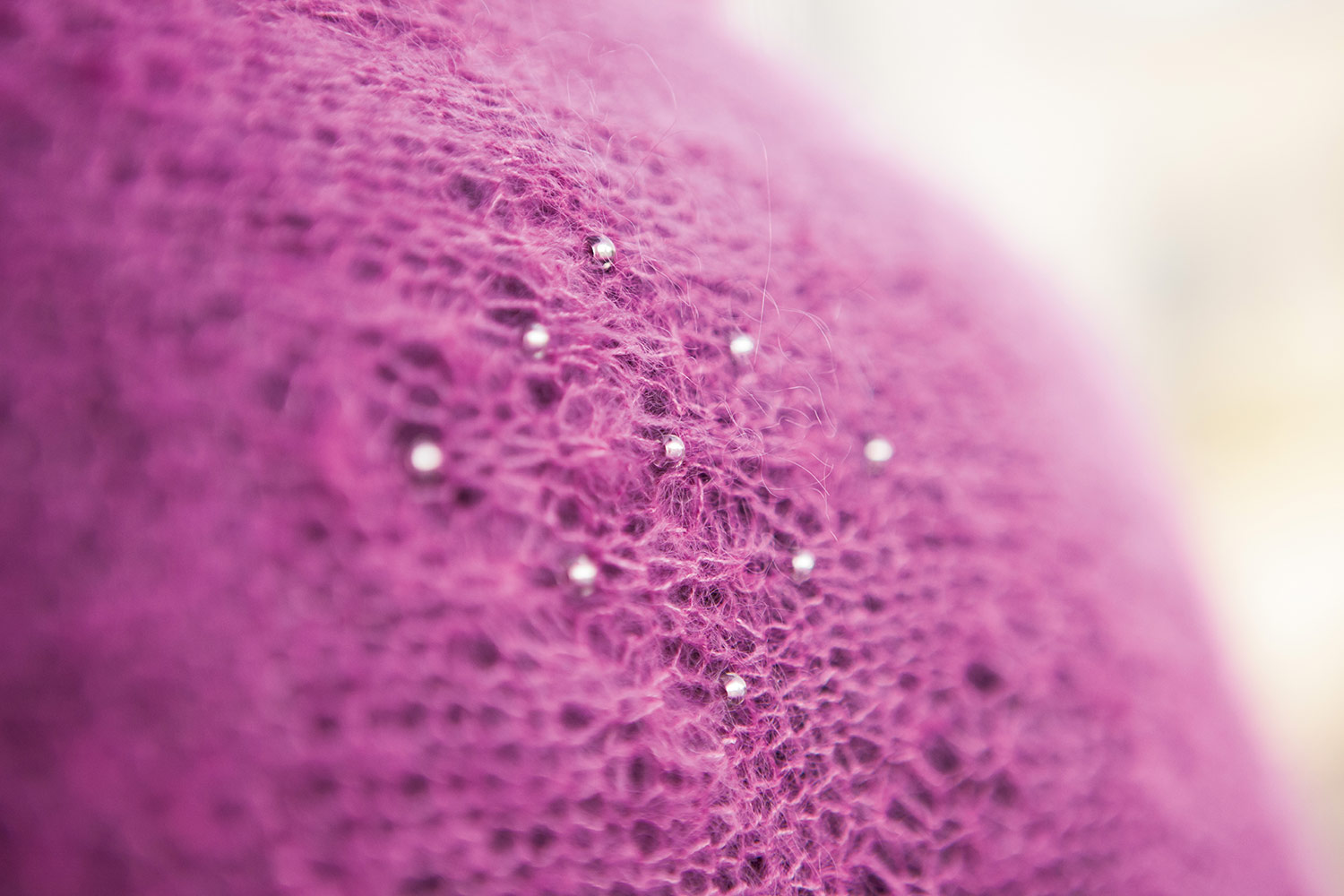 Detail of beads in a diamond shape showing on stocking stitch and tuck stitch fabric.