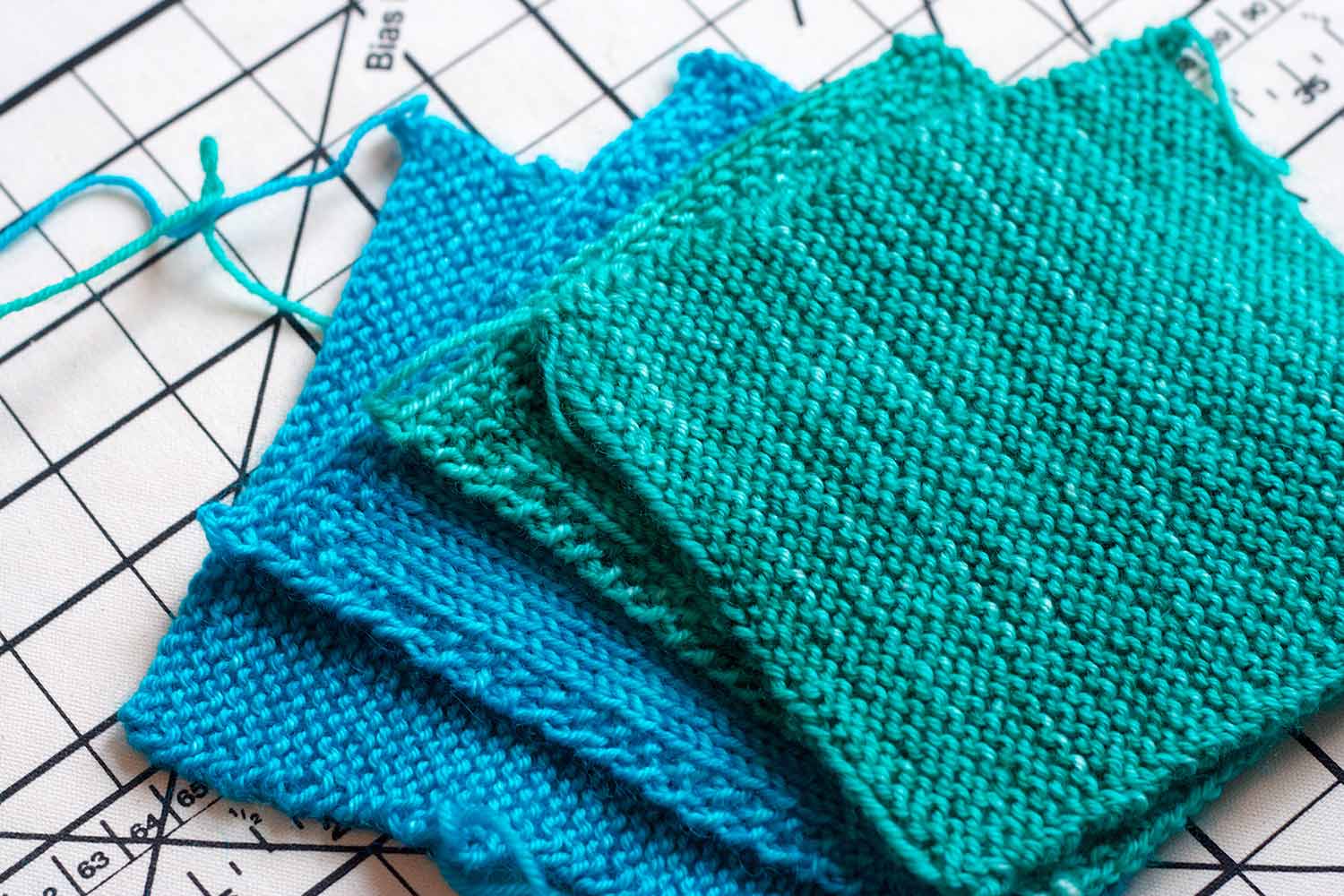 Stack of square swatches in garter stitch and stocking stitch in turquoise and light teal.