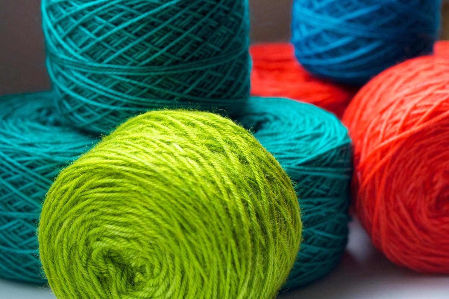 Playful stacking of several yarn cakes in bright colours.