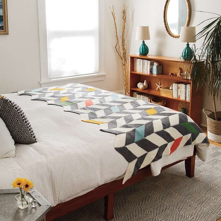 Modular knit blanket featuring chevrons and pops of colour.