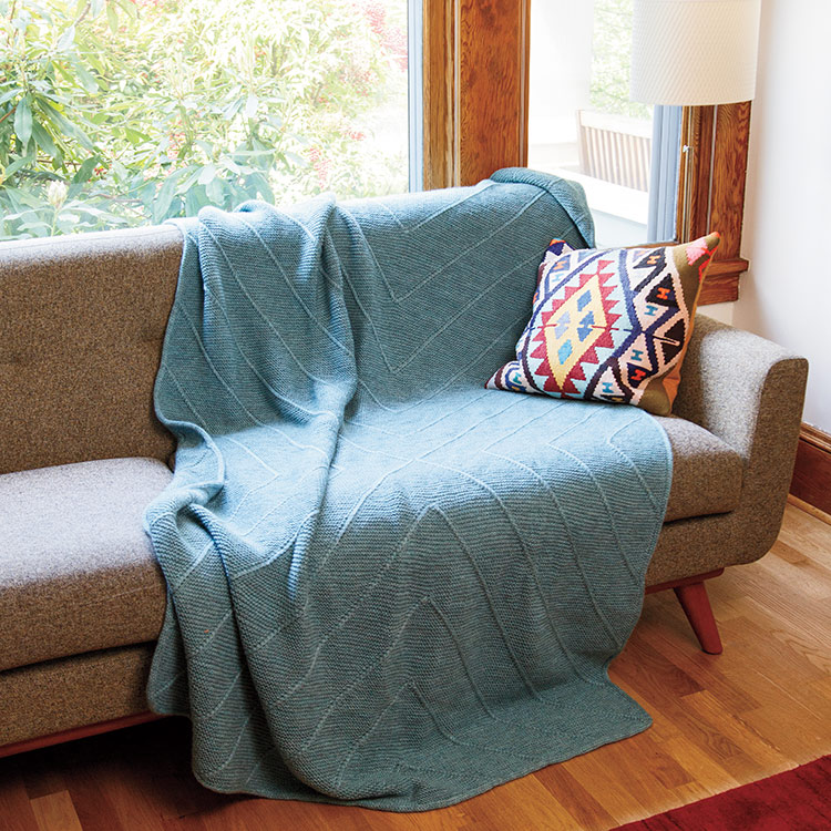 Blanket with textured diagonal lines created by a modular knitting technique.