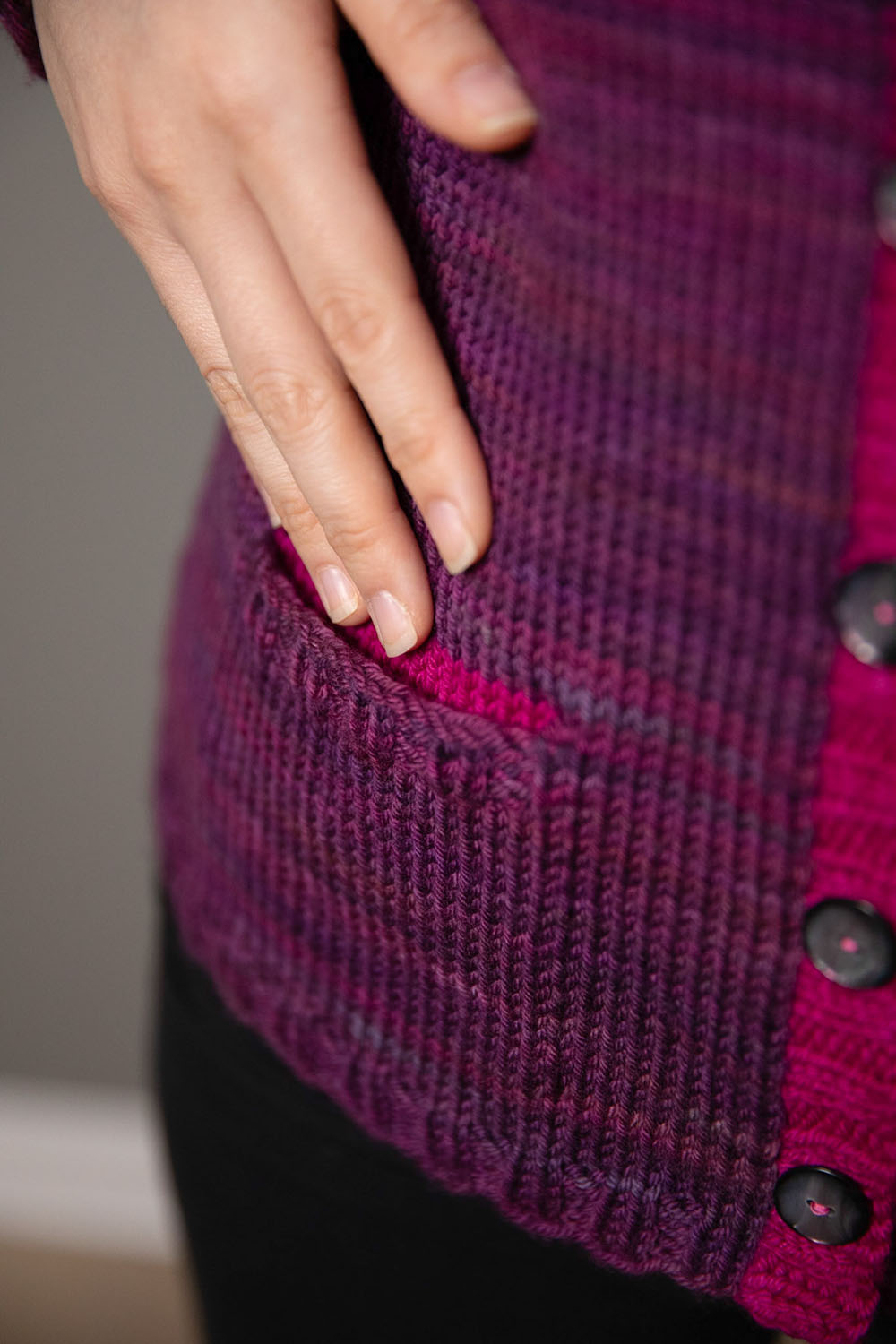 Detail shot of hand about to enter pocket on cardigan front.