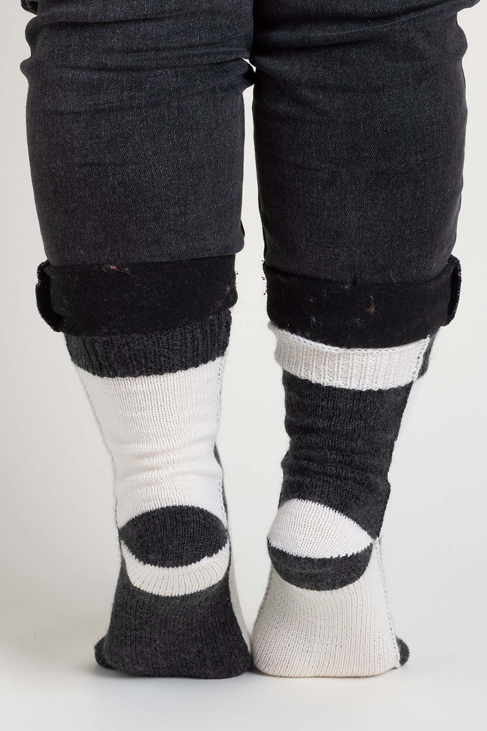 Back view of black and white colourblock socks worked flat; colour changes on each section of the sock.