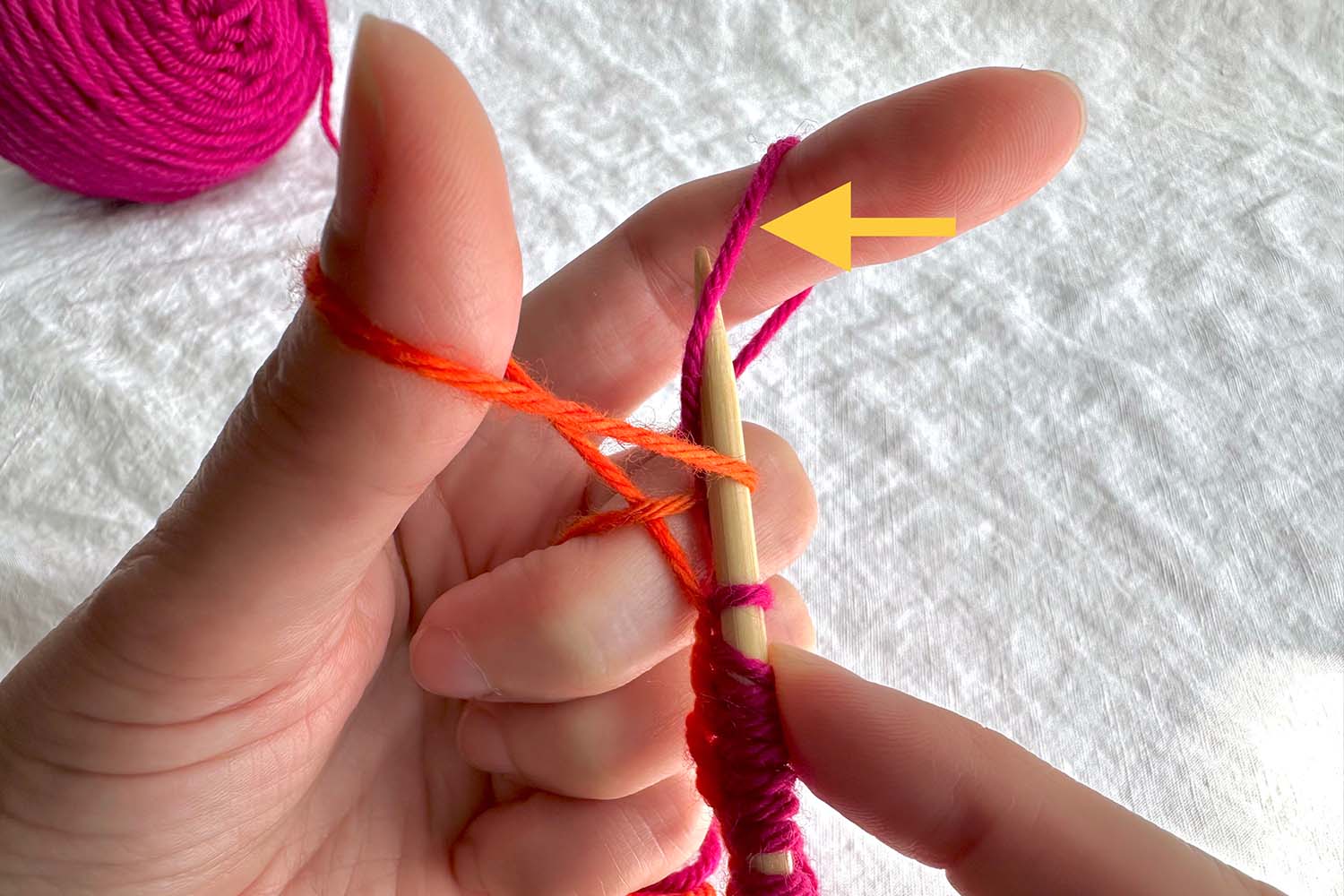 Needle inserted into finger loop with directional arrow.