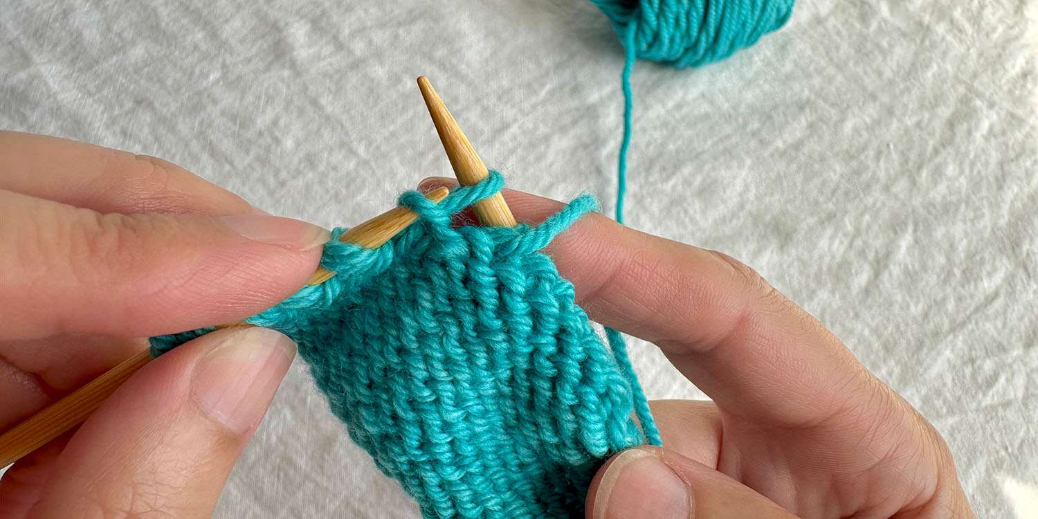 Left needle is inserted into stitch in row below last stitch on right needle.