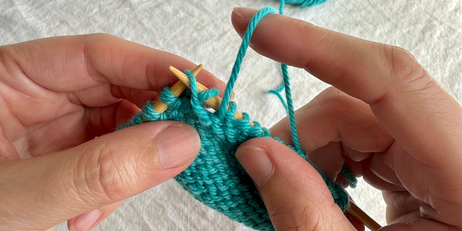 Right needle is inserted purlwise into raised stitch on left needle so it can be purled.