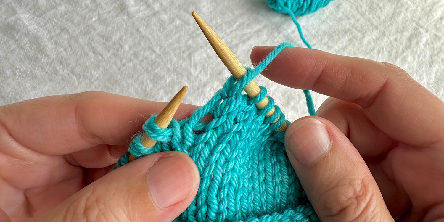 A knit stitch on right needle has been worked into a twin stitch and it is difficult to see the twin stitch.