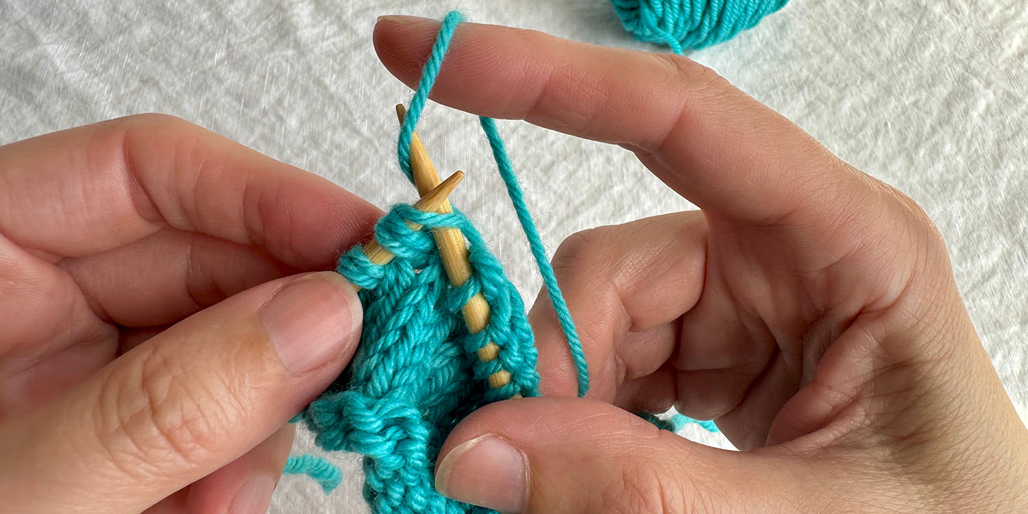 Raised stitch on left needle is in the process of being knit into.