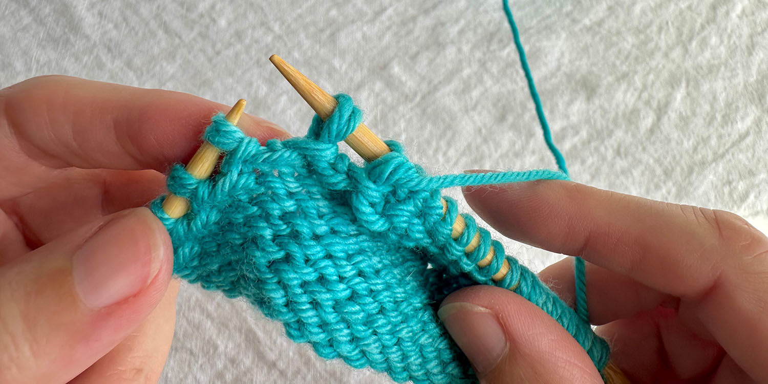 With wrong side facing, one twin stitch has been slipped to right needle, mid-row.