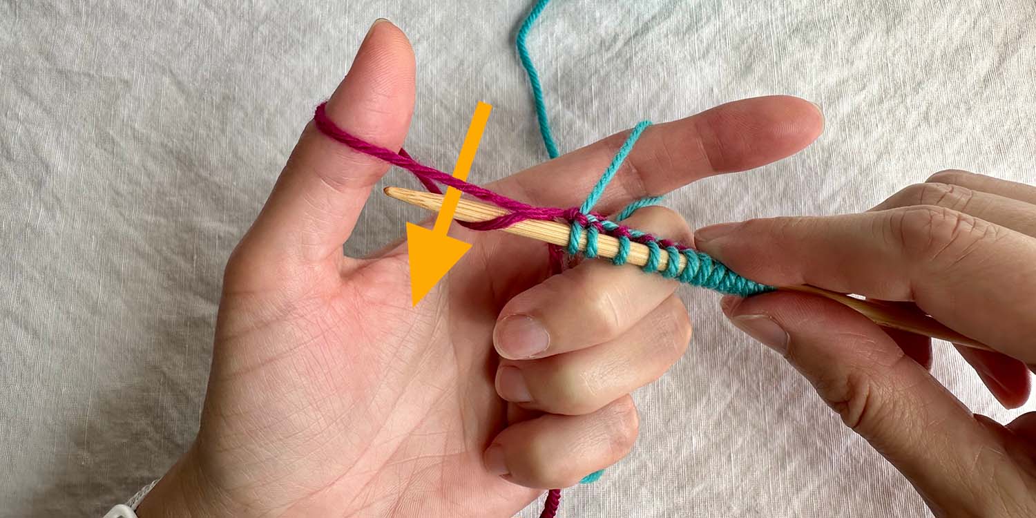 Needle inserted into middle of thumb loop from behind and above with directional arrow.