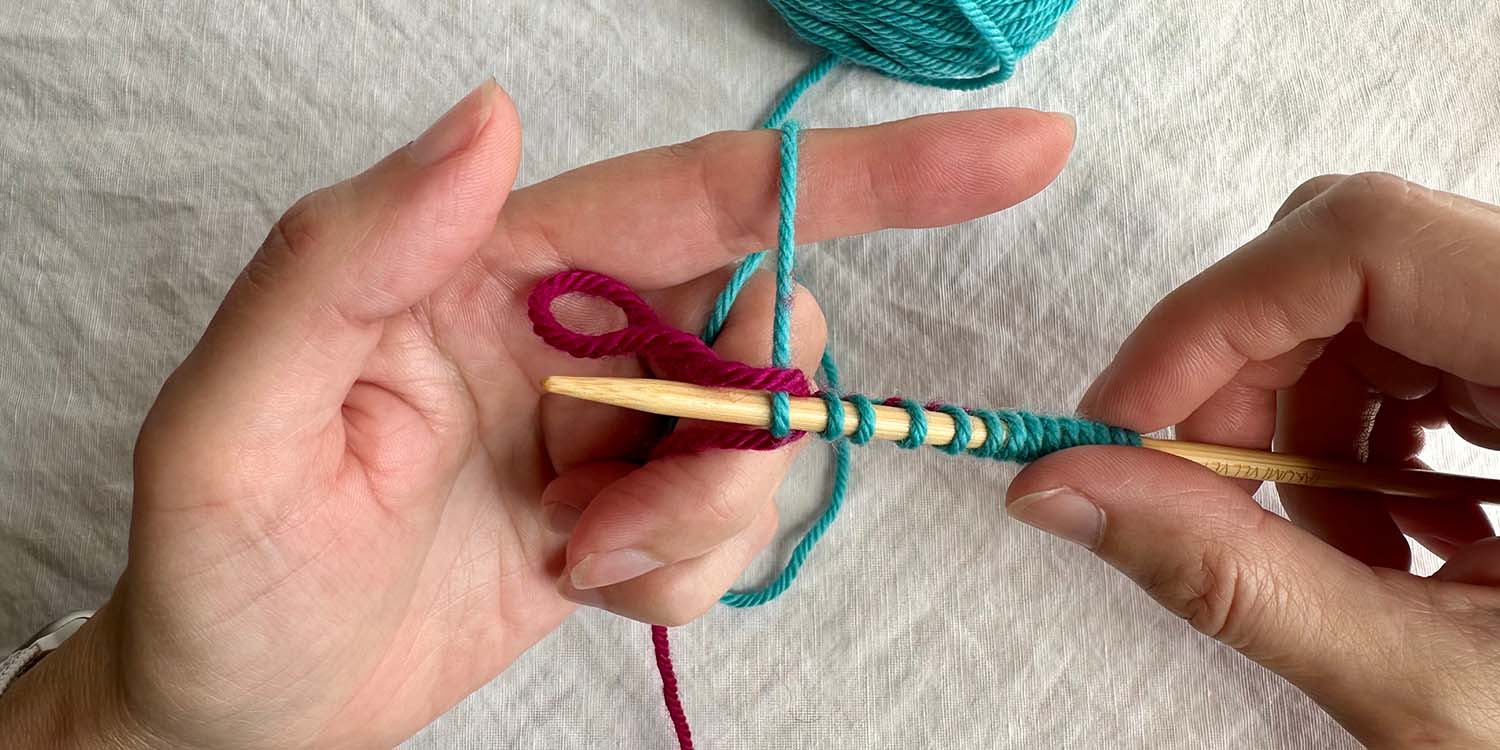 Thumb loop has been dropped off thumb while finger loop is still on finger and remaining fingers hold ends of yarn.