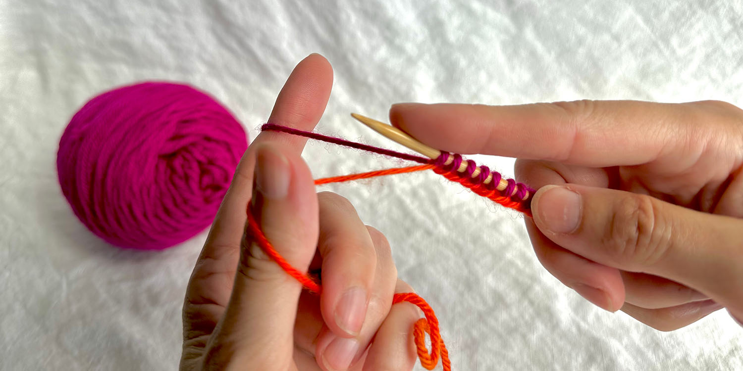 Two hands working a long tail cast on onto one needle; forefinger of right hand rests on needle in front of stitches on needle.